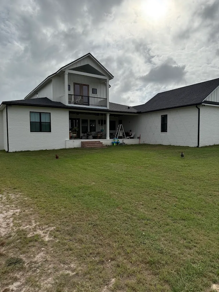 Rear view of a white home with a dark roof and black gutters.