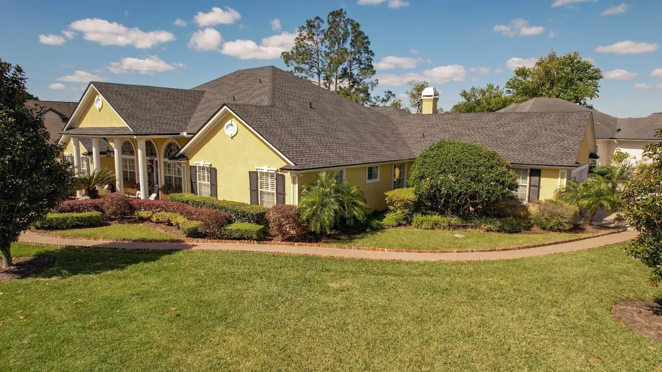 Front view of a yellow home with a broad gray shingle roof.