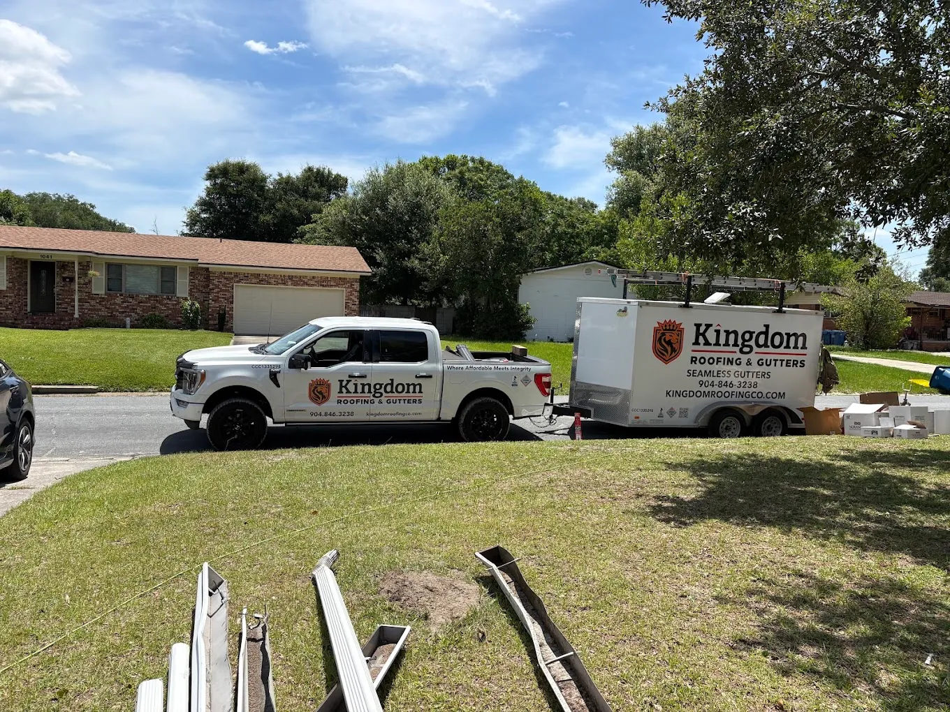 Kingdom Roofing truck and seamless gutter trailer at a residential jobsite.